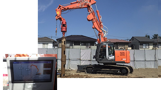 住宅に囲まれた敷地で稼働する建設機械と、その運転席のモニター